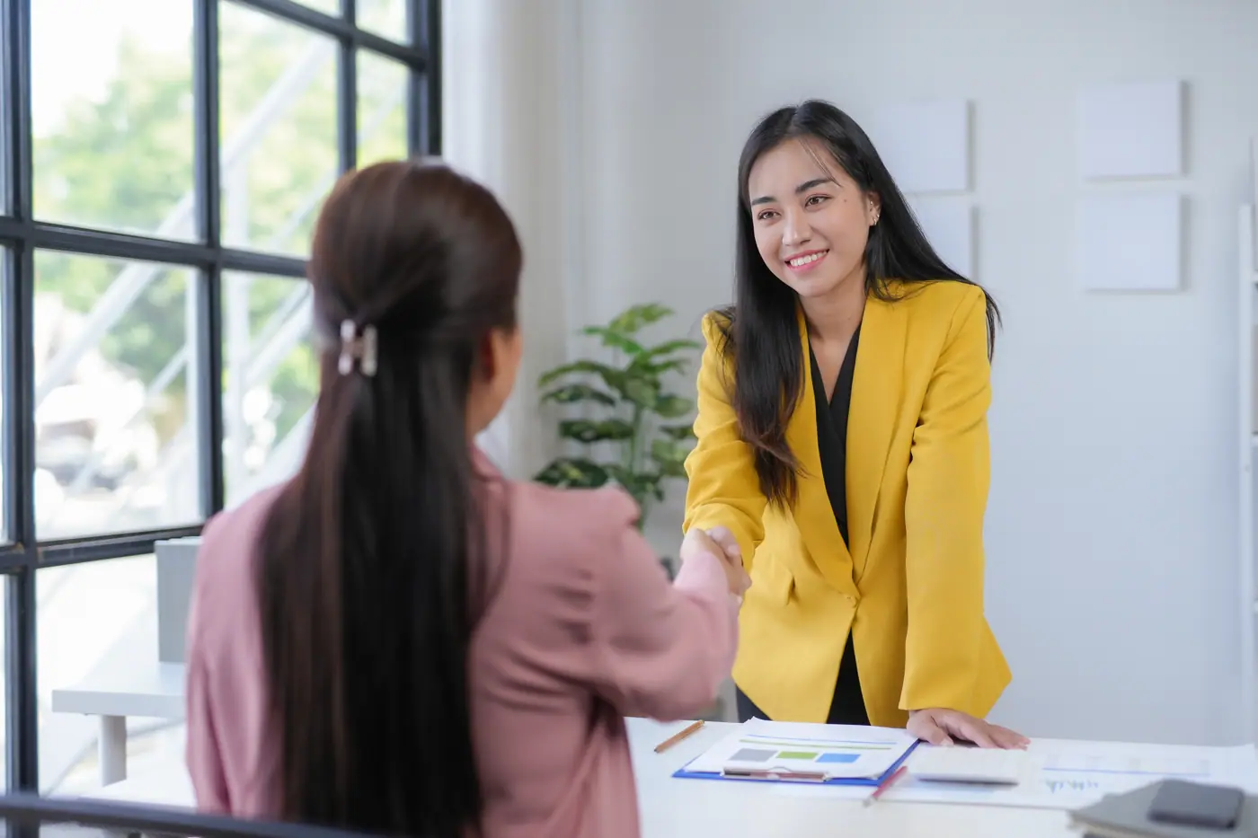 Two professionals shaking hands in a bright office